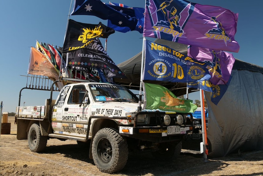 A white ute decorated with stickers and flags