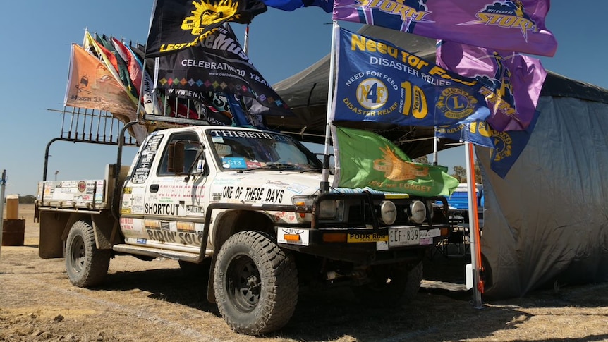 A white ute decorated with stickers and flags