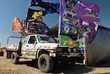 A white ute decorated with stickers and flags