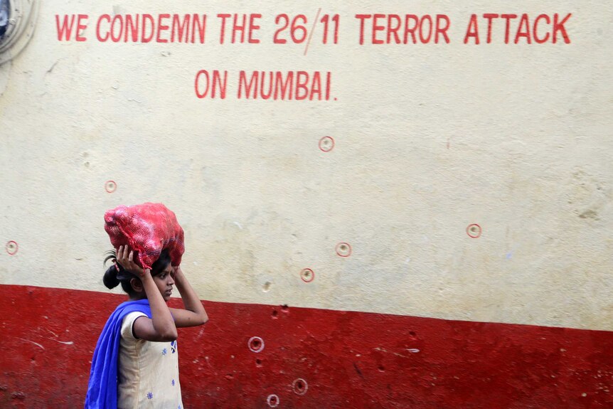 A girl walks past a wall in Mumbai that reads: 'We condemn the 26/11 terror attack on Mumbai'