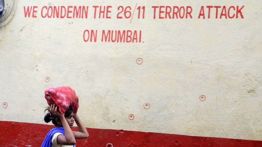 A girl walks past a wall in Mumbai that reads: 'We condemn the 26/11 terror attack on Mumbai'