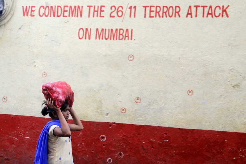 A girl walks past a wall in Mumbai that reads: 'We condemn the 26/11 terror attack on Mumbai'