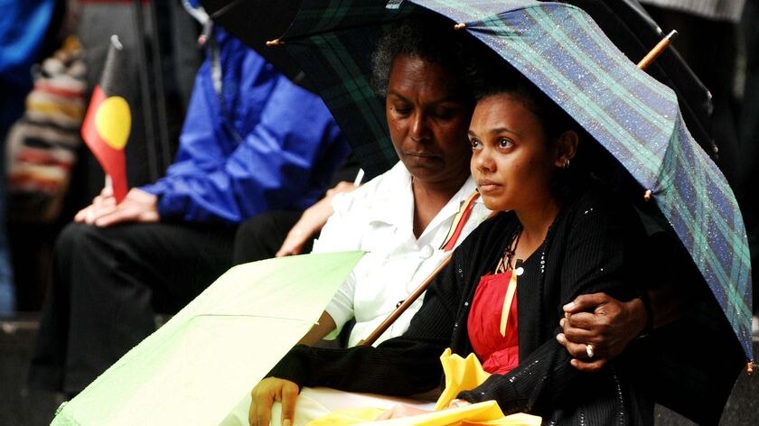 Two Indigenous women shelter from the rain