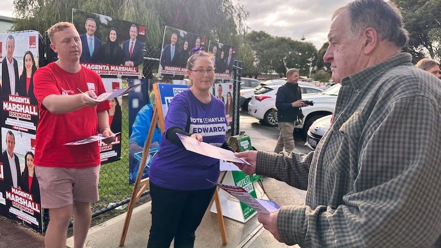 Campaigners hand a man pamphlets at a polling location. 