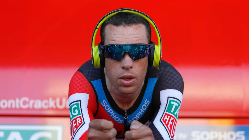 Richie Porte warms up on his time trial bike with his headphones on and sunglasses.