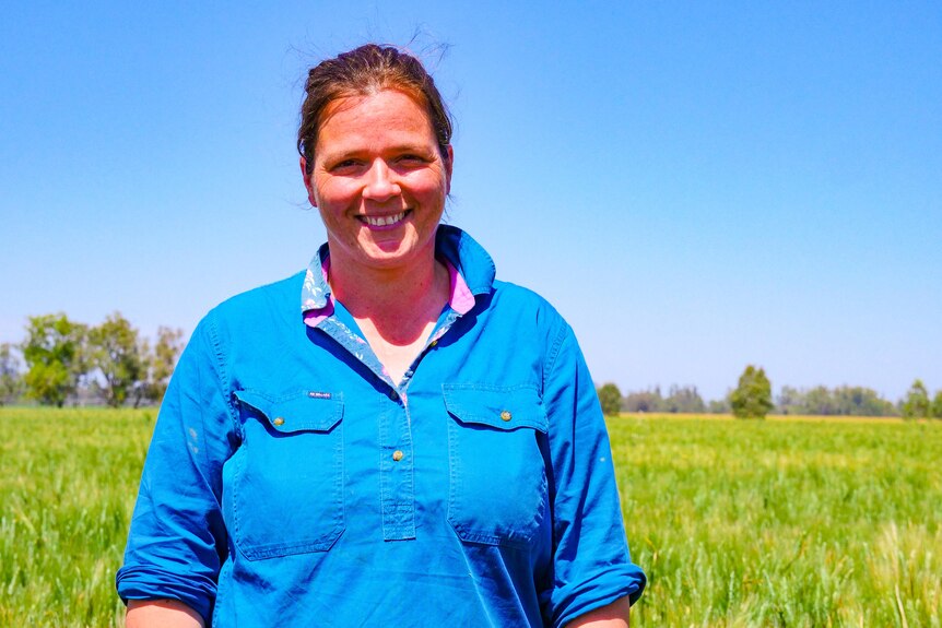 A woman in a blue shirt stands in a paddock