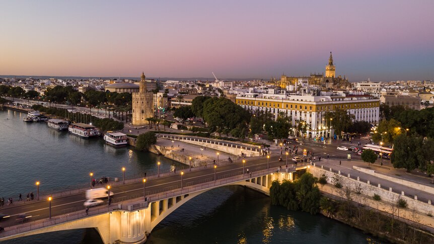 sunset over Seville cityscape, with river and bridge 