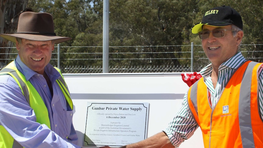 Gunbar Water's Don Low and Nayce Dalton from Murrumbidgee Irrigation shake hands while holding a plaque at pipeline launch