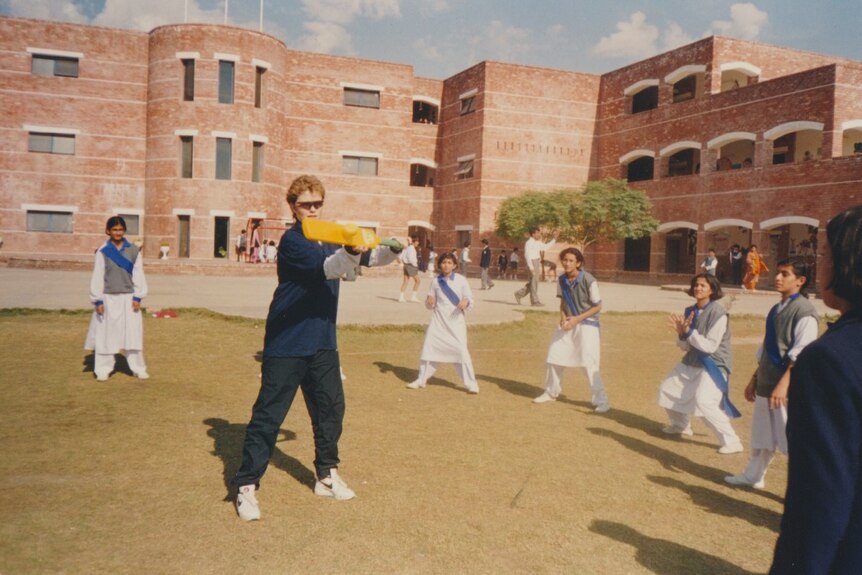 Davis plays a cross-bat shot as a schoolgirl throws a cricket ball her way