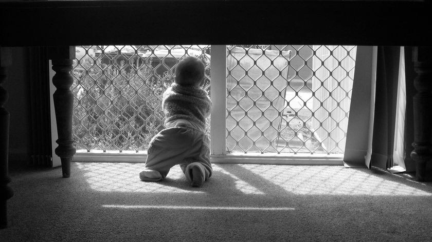 Black and white photo of child looking out window - generic child neglect no faces