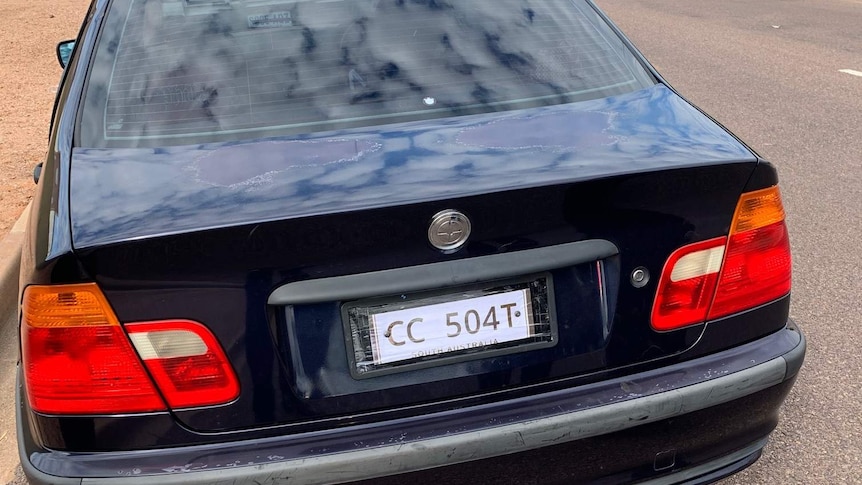 A dark navy BMW sedan with white paper number plates