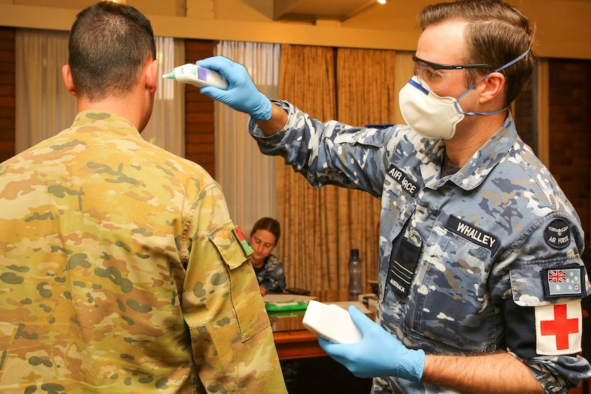 Air Force medical personnel checks an ADF member's temperature.