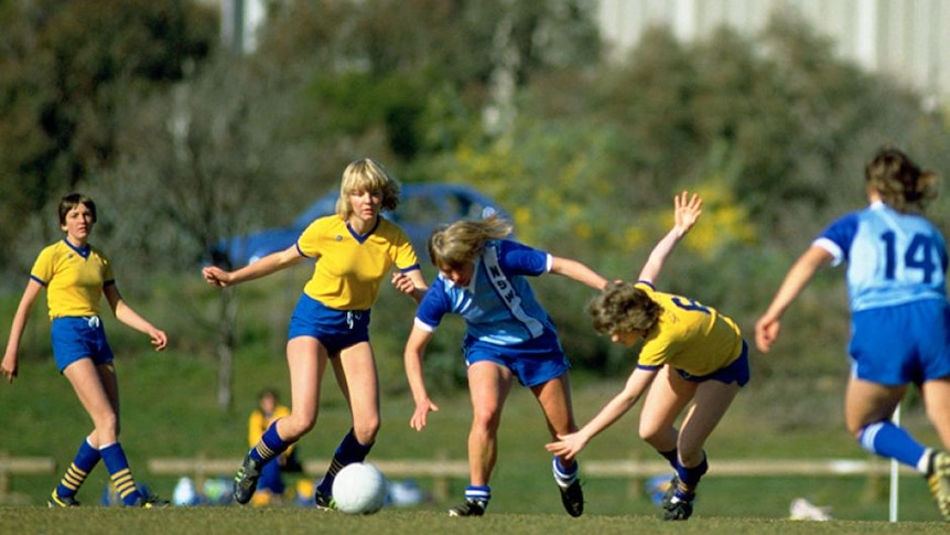 an old picture of women  playing soccer opn a soccer field during the day