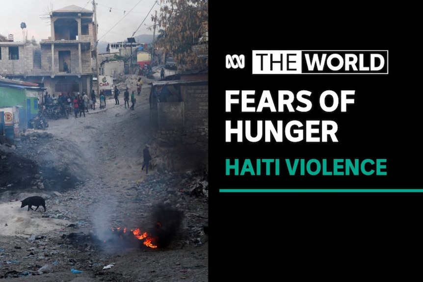 Fears of Hunger, Haiti Violence: A burning pile in a street. People mingle in the background.