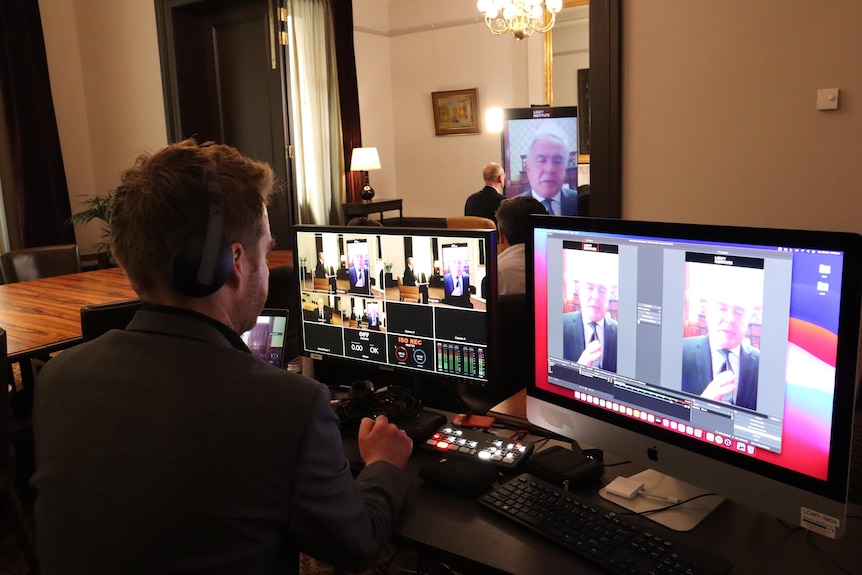 A panel operator works on his computer with the interview with Kurt Campbell being broadcast on screen via video link.  