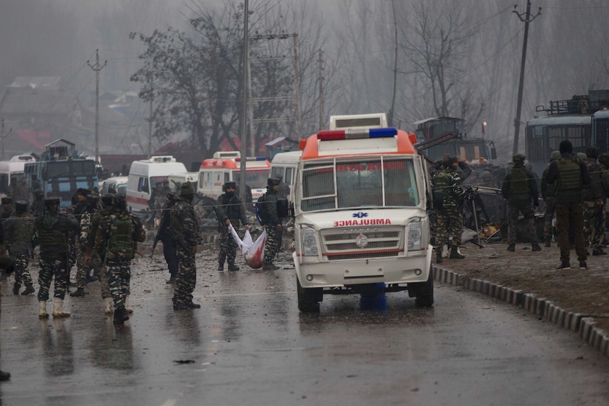 Indian paramilitary soldiers patrol near the site of the explosion, assisted by ambulance.