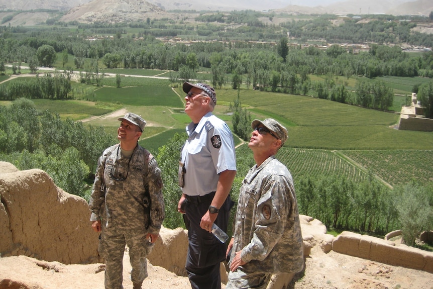 Three men, two in military uniform and one in AFP uniform, stand outdoors in Afghanistan.