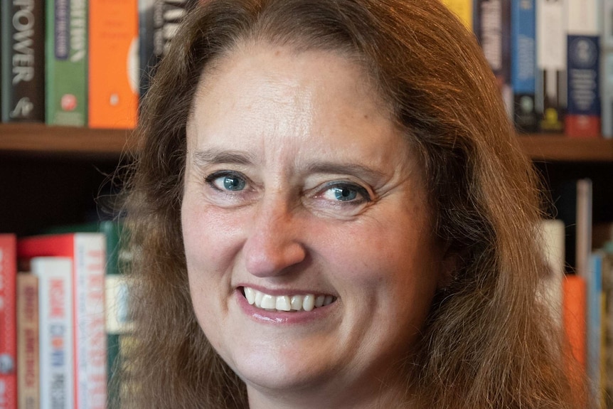 A headshot of a woman with books in the background