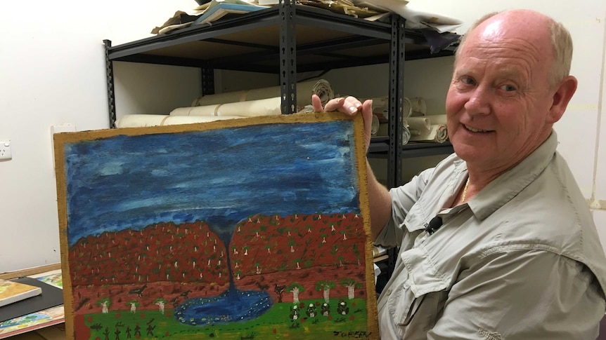 Greg Crofts holding Jack Green's painting in a store room