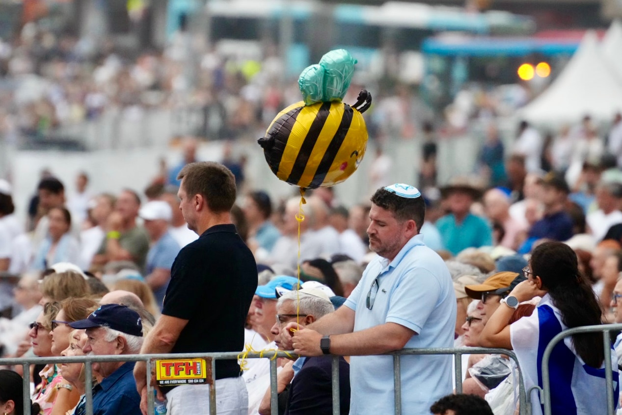 Um homem usando um kipá segurando um balão de abelha.