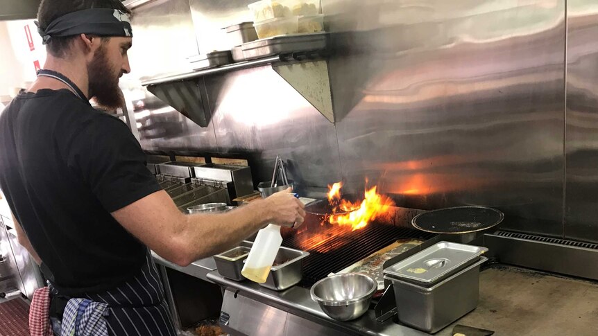 A chef works in the kitchen of barbecue joint Elwoods Eatery in Orange