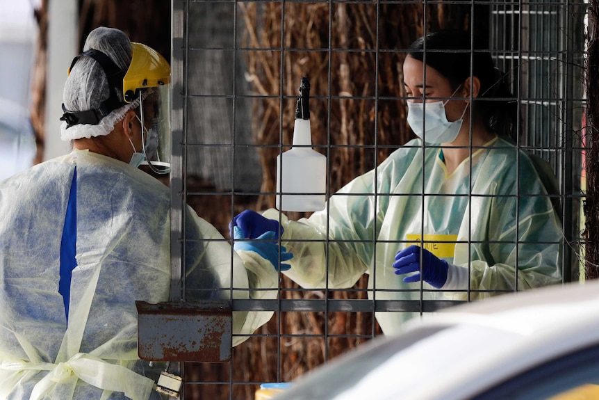 Medical staff prepare to take a COVID-19 tests at a drive through.