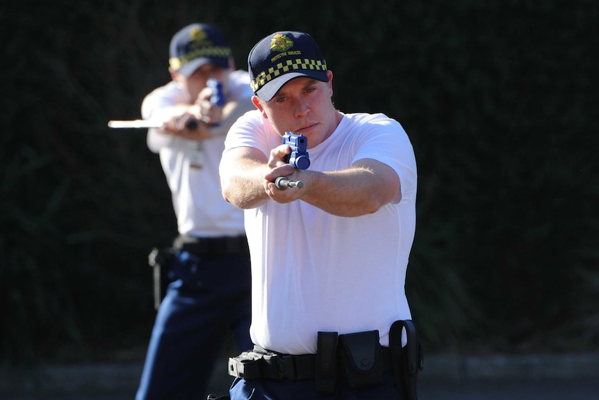 PSO officers point weapons towards a camera during a training exercise.