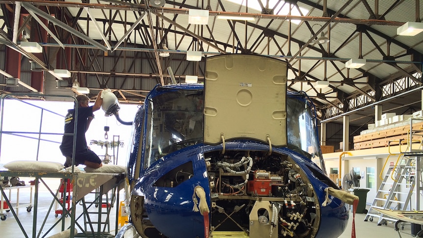 A Careflight engineer takes one of the helicopters to pieces inside Hangar 6.