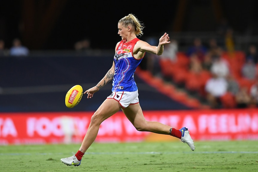 A Melbourne Demons AFLW players kicks the ball against the Lions.