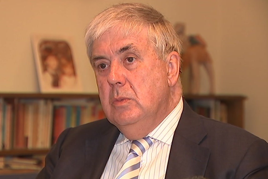 A headshot of a man with grey hair wearing a suit.