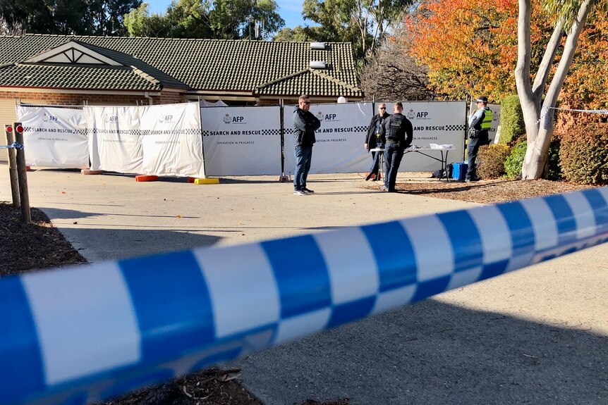 Police crime scene tape infront of police officers.