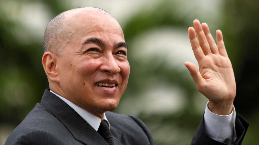 Cambodia's King Norodom Sihamoni waves to crowds from his car during the day