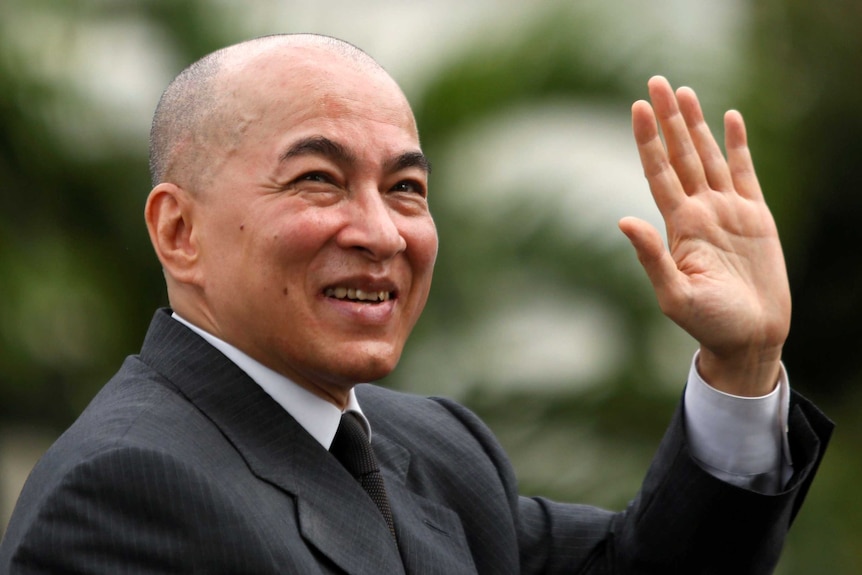 Cambodia's King Norodom Sihamoni waves to crowds from his car during the day