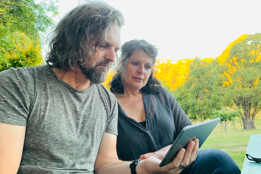 A man and woman hold an ipad