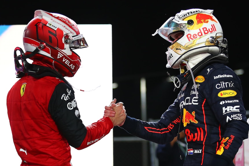 Two race car drivers, out of their car, embrace in congratulations.