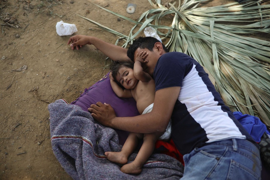 A young migrant child rests with his father