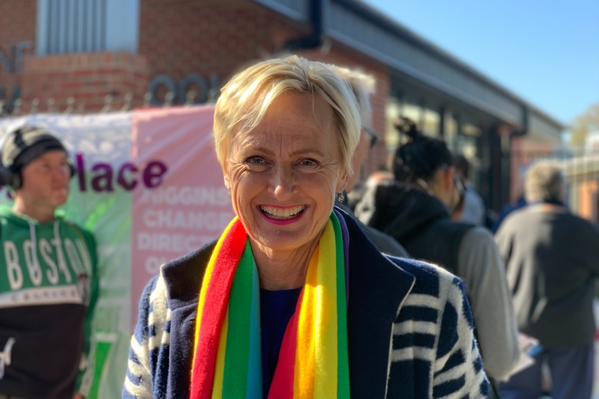 Liberal MP Katie Allen, wearing a rainbow scarf, smiles at the camera.
