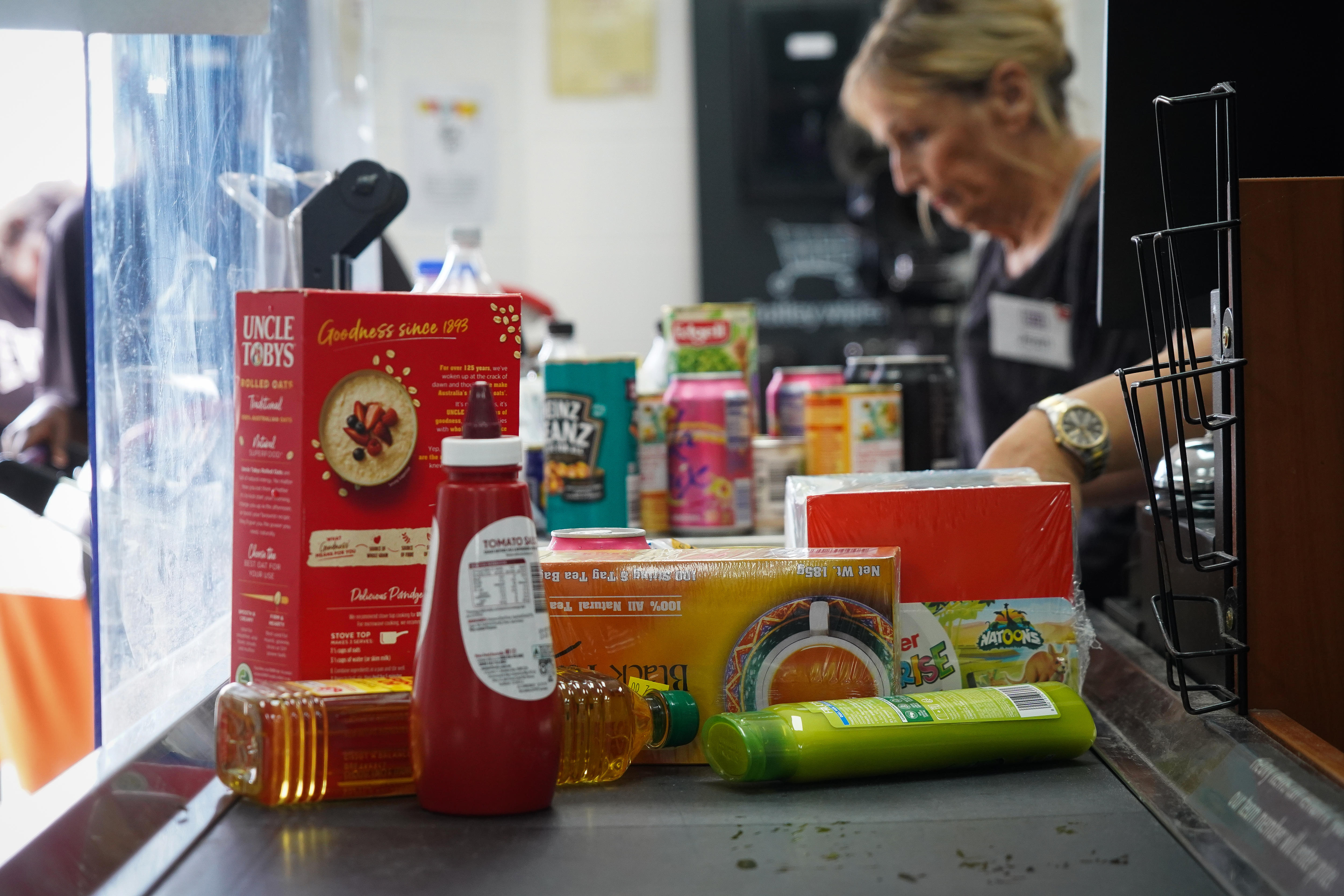 A checkout stacked with groceries including tomato sauce and shampoo