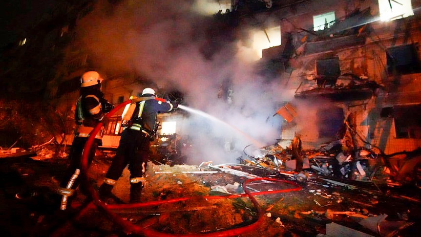  Firefighters hose down burning burning debris in front of a damaged building following a rocket attack.