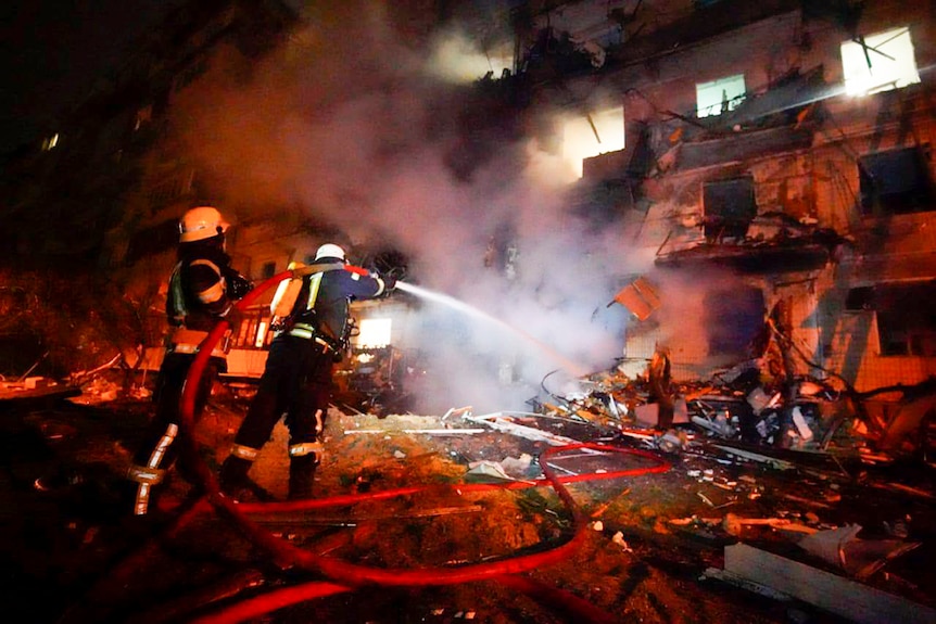  Firefighters hose down burning burning debris in front of a damaged building following a rocket attack.