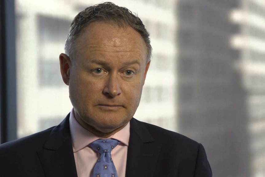 Head shot of ASIC Commissioner Sean Hughes sitting in his office, with blurry background.