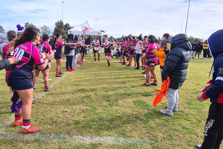 A man leads a team on to the field for a rugby league match