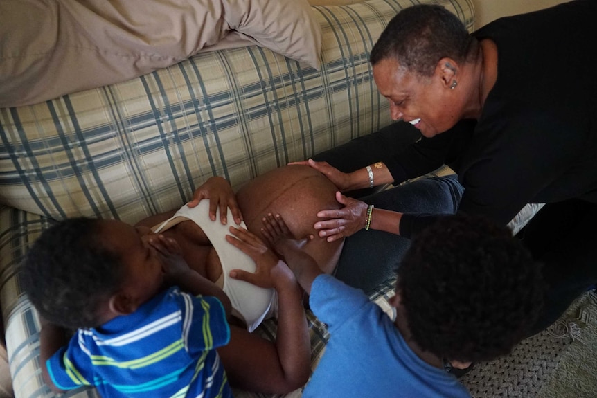 Binahkaye Joy's kids cluster around their heavily pregnant mother as she is checked by midwife Claudia Booker.
