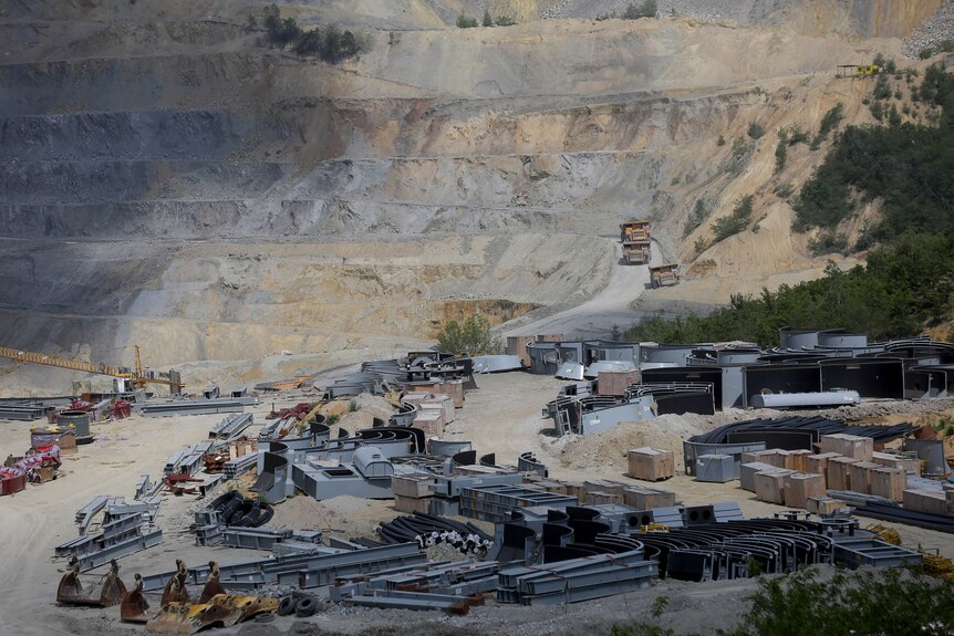 An open mine with vehicles driving down one of its roads. 