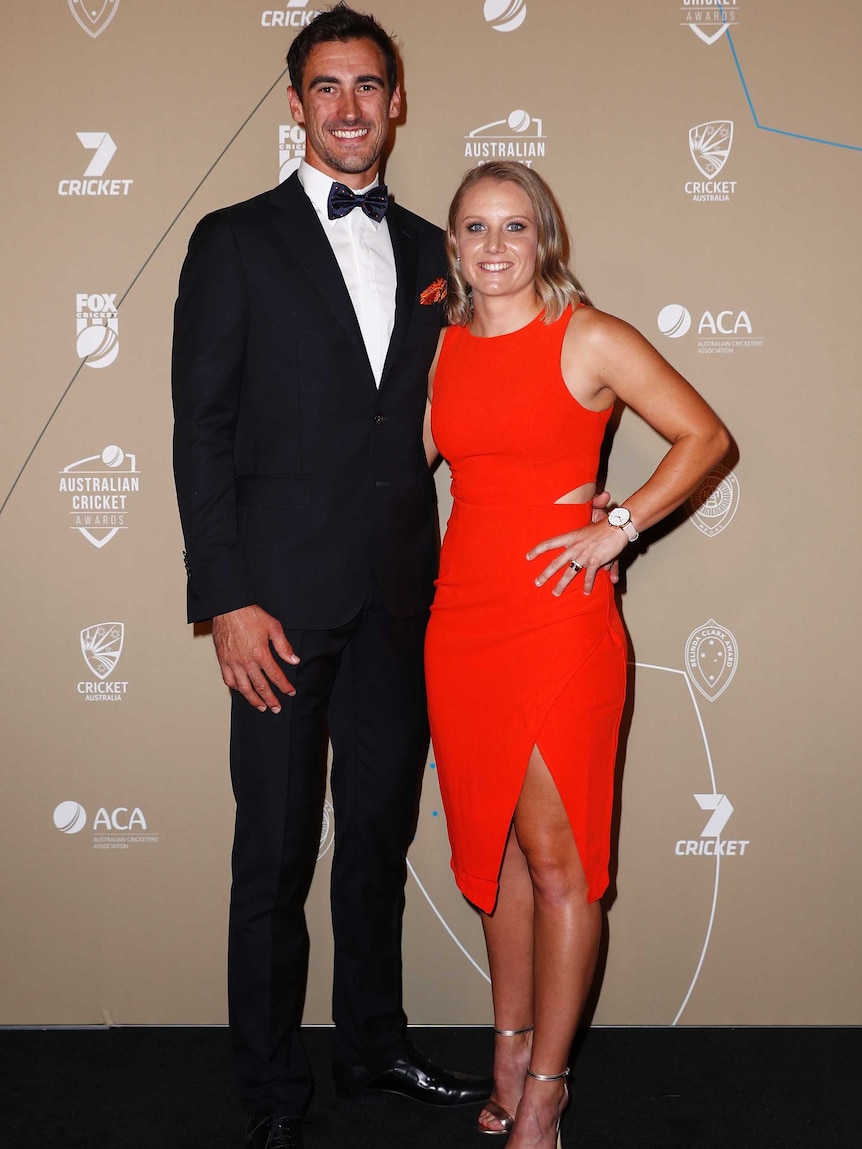 An Australian male and female cricketers pose for photographers at an awards night.