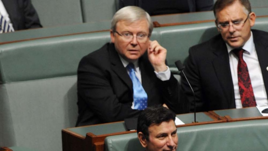 Kevin Rudd sits in the background in the House of Representatives while Prime Minister Julia Gillard talks to ministers in the foreground on March 21, 2013.