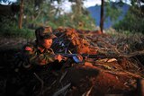 A rebel soldier holds his weapon as he looks from an outpost on the Laja Yang frontline in northern Burma.