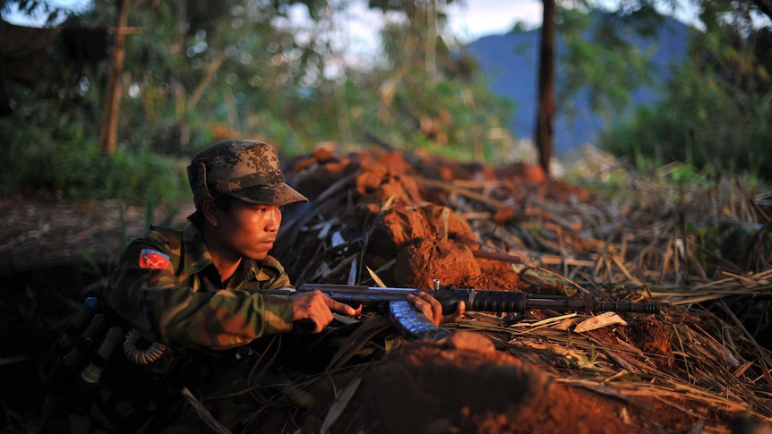 A rebel soldier holds his weapon as he looks from an outpost on the Laja Yang frontline in northern Burma.