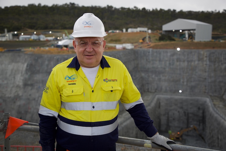 A middle-aged man wearing a hard hat on the edge of a tunnel boring facility