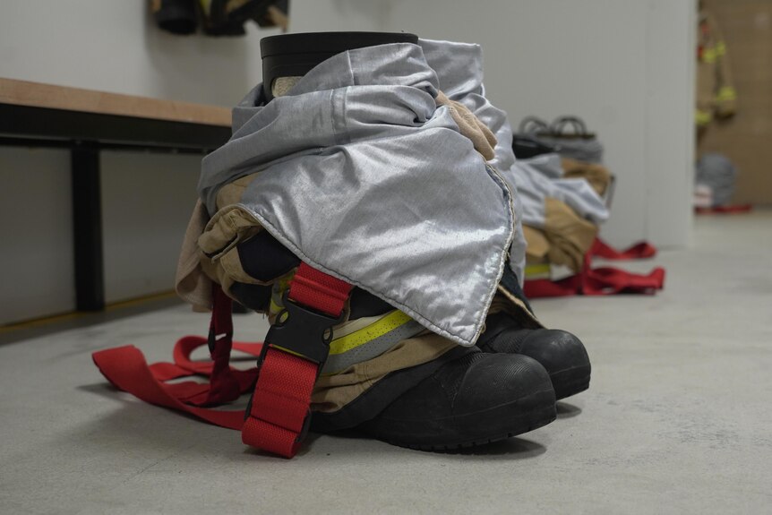 A pair of firefigthter boots sits on the concrete ground of a fire station